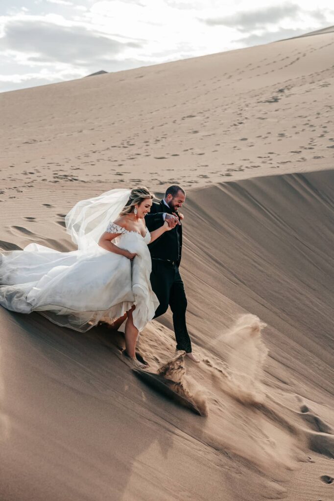 a couple running down a sand dune during their great sand dunes elopement