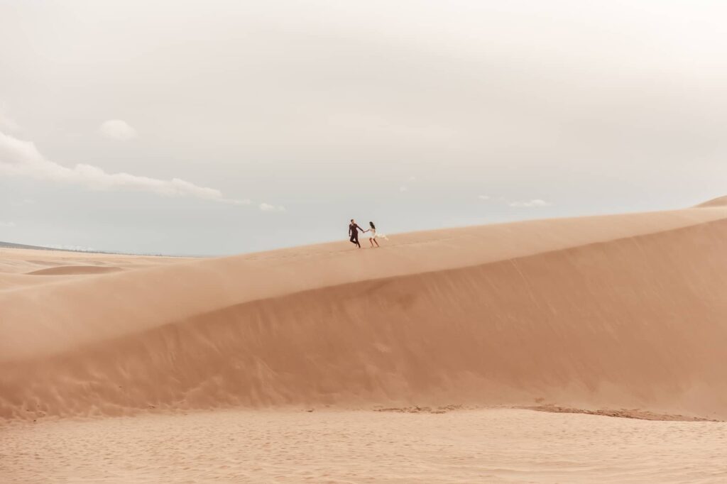 Photo of a couple running on top of a dune during the great sand dunes elopement