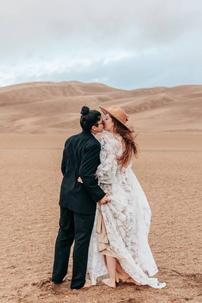 a couple in wedding attire kissing during their great sand dunes elopement